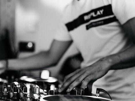 A DJ working at a mixing console. The atmosphere is dynamic and full of energy.
