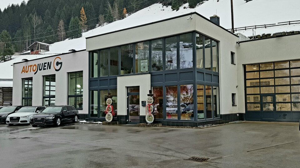 A modern car dealership with large windows and a bright facade. Surrounded by a snow-covered landscape.