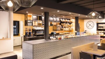 A modern café with an eye-catching counter and an inviting atmosphere. The decor is stylish and bright, with various display shelves.
