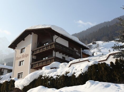 A cozy house in the mountains, surrounded by snow and fir trees. The snow-covered landscape radiates tranquility and beauty.