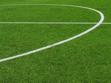 A close-up of a soccer field with green artificial turf. The white lines indicate the playing area.