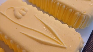 Two yellow butter pieces with floral patterns. The surface is smooth and shiny.