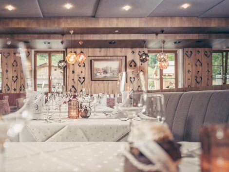 A cozy restaurant with elegantly set tables. Soft lighting and rustic elements create an inviting atmosphere.