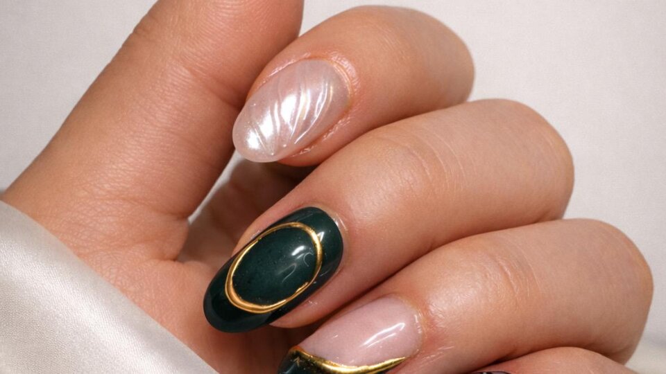 A hand with artistically designed nails in various colors. The nails are adorned with golden and black details.