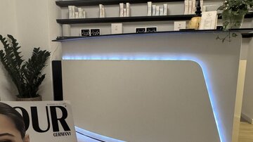 A modern reception area with a stylish, illuminated counter. In the foreground lies a magazine focused on beauty topics.