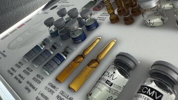 A collection of vials and ampoules on a laboratory table. The vials are labeled differently and contain various solutions for medical applications.