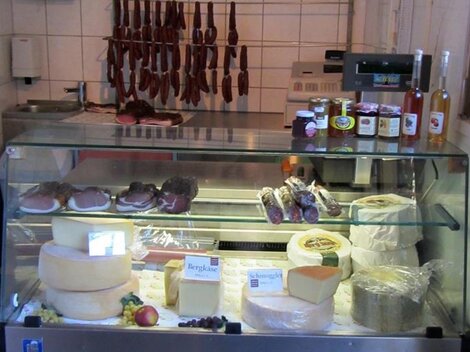 A refrigerator with various types of cheese, cold cuts, and some bottles. The selection looks fresh and inviting.