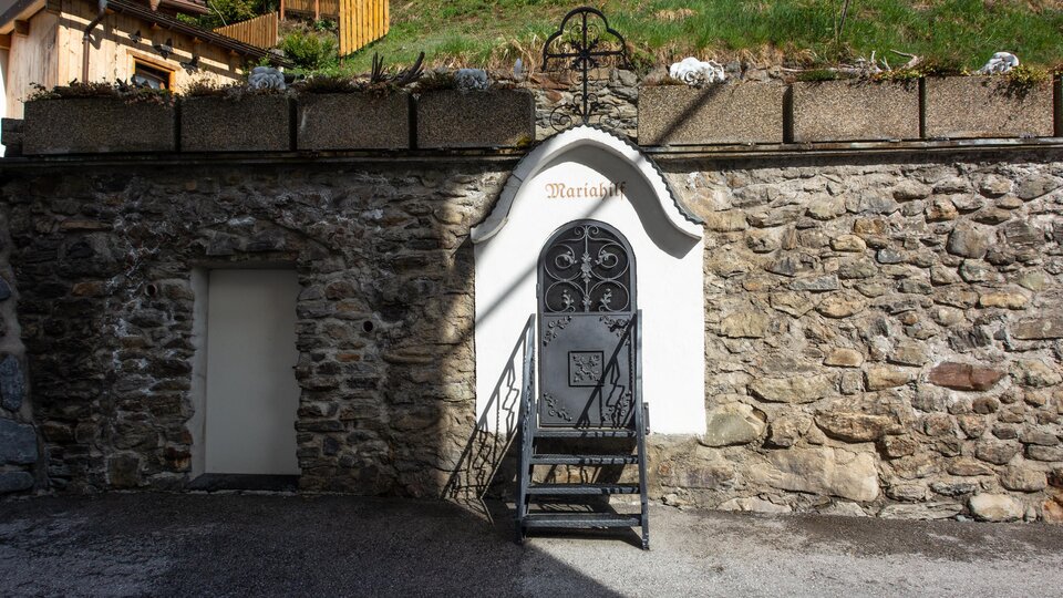 A historic stone building with a black staircase and a decorative door. At the top, the word "Maria" is visible. | © Bernhard Gruber – Photography