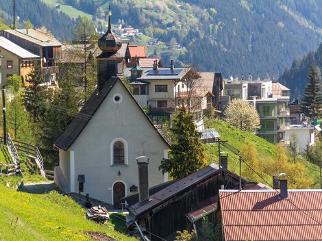 A picturesque village in the mountains with a small church. The surroundings are green and surrounded by impressive hills. | © Bernhard Gruber – Photography
