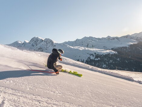 A skier glides over a snowy slope in the mountains. In the background, impressive mountain landscapes can be seen.