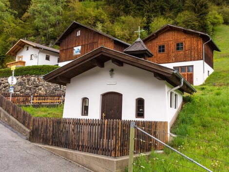 A picturesque village with traditional wooden houses and a small church. Surrounded by green meadows and trees. | © Bernhard Gruber – Photography
