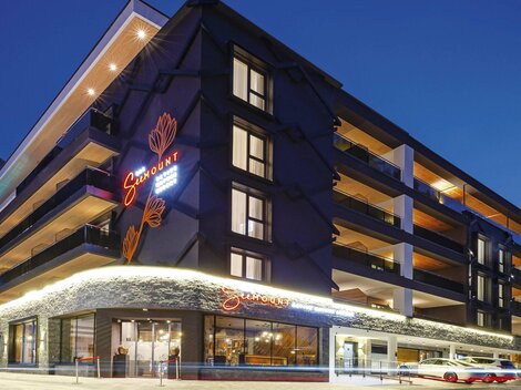 A modern hotel building at night with a illuminated facade. The windows reflect the atmospheric light of the surroundings.