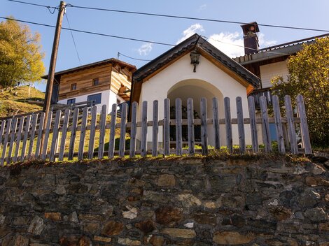 A charming house with a wooden fence and a picturesque location. Surrounded by nature and mountains, it radiates coziness. | © Bernhard Gruber – Photography